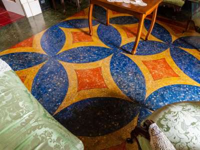 Il nostro sguardo viene attratto dalla sinuosa fantasia a mosaico policromo blu, rossa e dorata del pavimento
